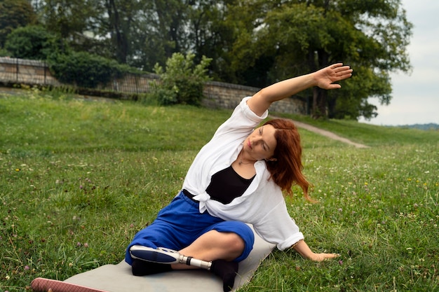 Foto mujer con prótesis de pierna haciendo yoga