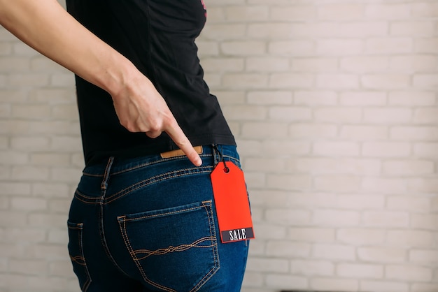 Foto la mujer se prueba la ropa y señala la etiqueta del viernes negro. concepto de compra, descuentos de temporada.