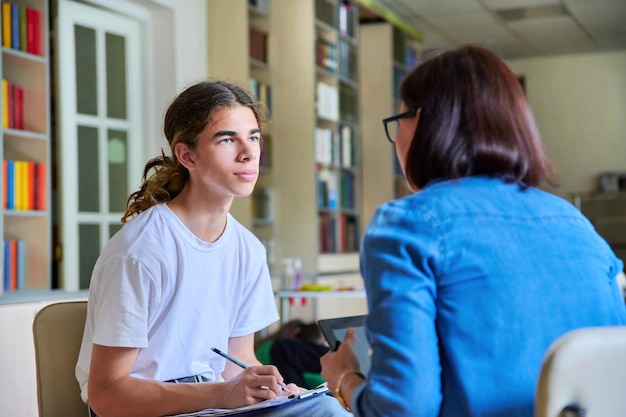 Foto mujer psicóloga escolar hablando y ayudando a estudiante adolescente varón