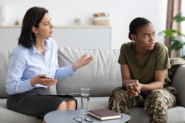 Mujer psicoterapeuta hablando con una soldado negra durante una reunión en el cargo