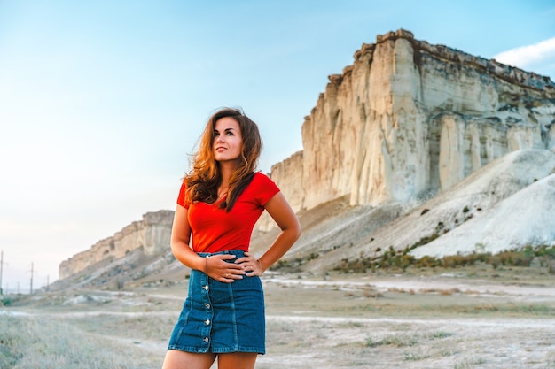 Mujer en la puesta de sol sobre el fondo de una roca blanca