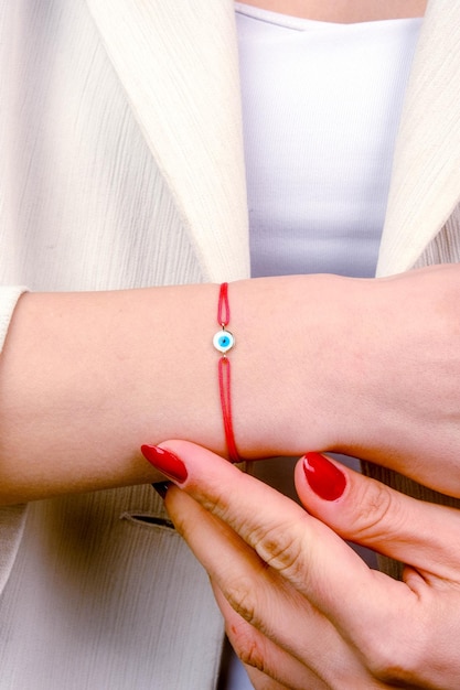 Foto una mujer con una pulsera roja con una piedra azul en su muñeca