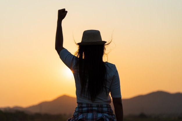 Mujer con el puño en el aire durante el concepto de puesta de sol, libertad y coraje.