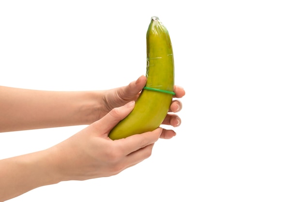 La mujer se puso un condón en un plátano aislado en un fondo blanco