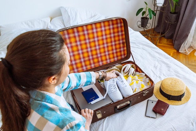 La mujer puso la ropa en la maleta con el pasaporte, la computadora portátil, los boletos, el concepto de viaje espacial.