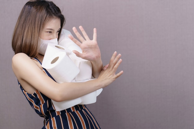 La mujer que abastece de papel higiénico para la cuarentena doméstica, sostiene muchos rollos de papel higiénico en la mano.