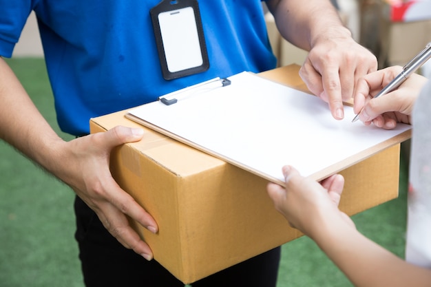 Mujer que acepta una entrega de cajas de cartón del repartidor.