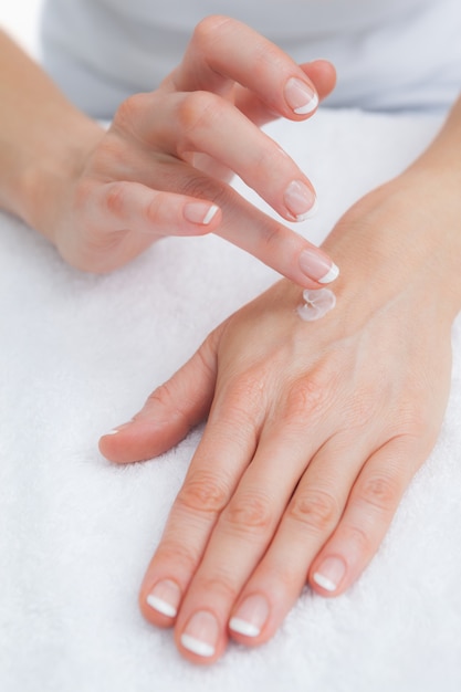 Mujer que aplica la crema en la mano