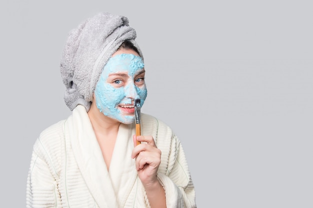 Mujer que aplica la máscara facial de arcilla en el salón de spa o en casa, tema de cuidado de la piel. Mascarilla facial, tratamiento de belleza spa con espacio de copia