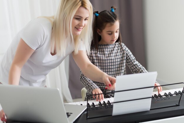 Mujer que ayudaba a su hija a tocar el piano, el cuerpo y los botones del piano fueron modificados digitalmente