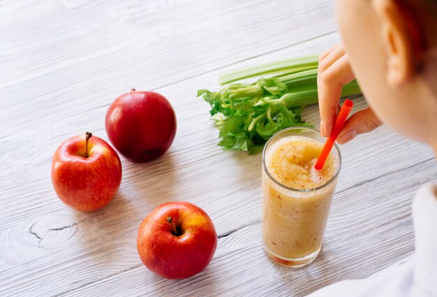 Mujer que bebe un batido de manzanas y apio en la mañana, vista desde arriba