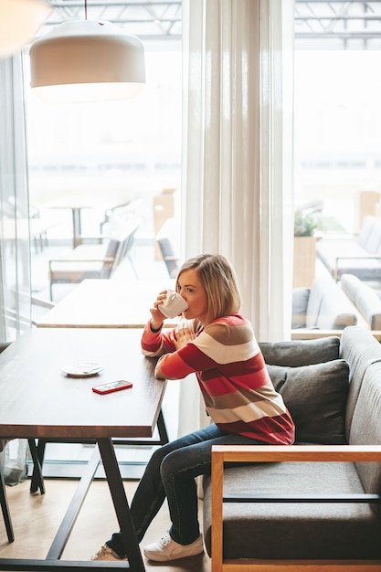 Mujer que bebe el café en café