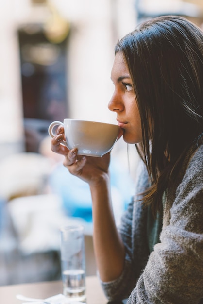 Mujer que bebe el café en café