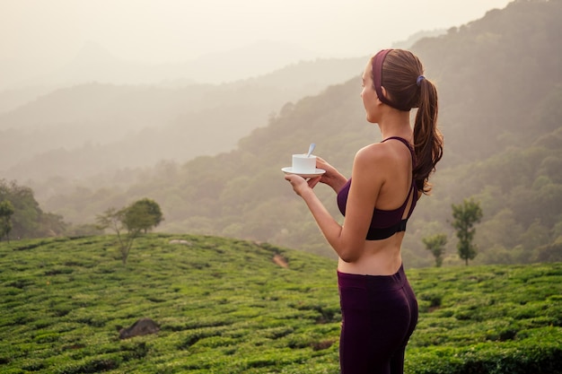 Mujer que bebe la fábrica de tazas de té en la India Munnar