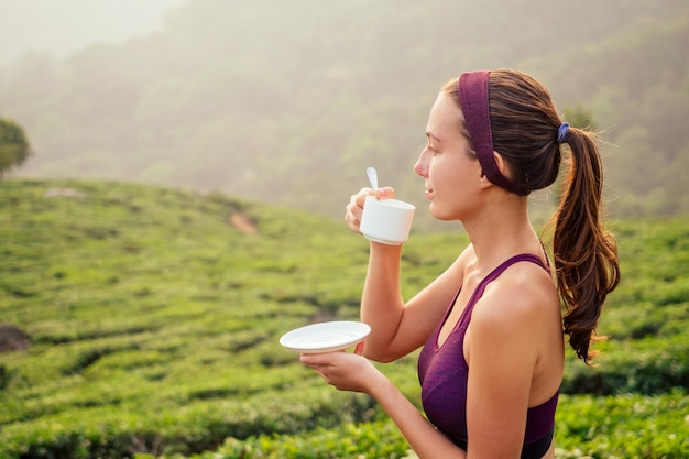 Mujer que bebe la fábrica de tazas de té en la India Munnar