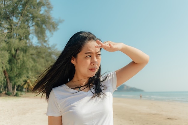 Mujer que camina a lo largo de la playa bajo el día soleado de verano.