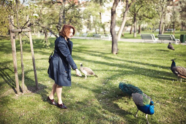 Mujer que camina entre los pavos reales en un parque público en Praga