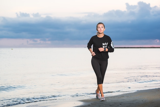 Mujer que corre en la playa al amanecer