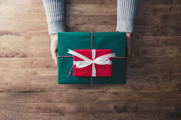 Mujer que da las presentes cajas rojas y verdes para regalo de navidad.