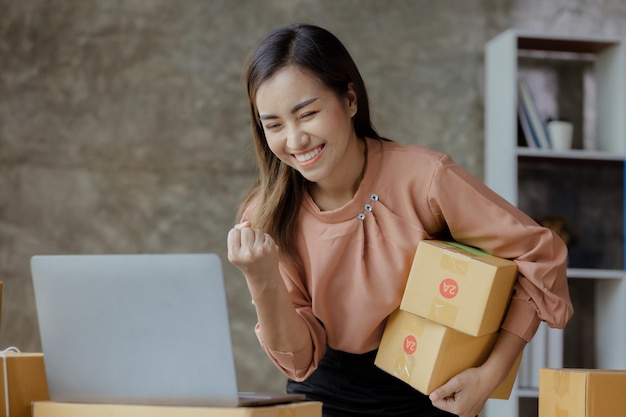 La mujer que dirige una tienda en línea con una cara feliz debe verificar las ventas que vende en línea y empaqueta los productos a través de un concepto de empresa de transporte privado de una mujer que abre un negocio en línea