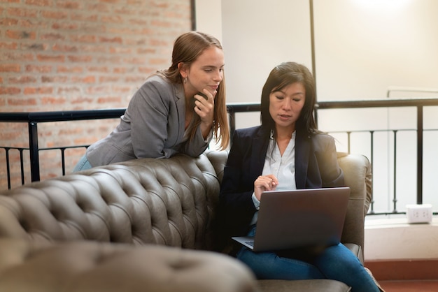 Mujer que discute casualmente ideas en el sofá en lugar de trabajo moderno