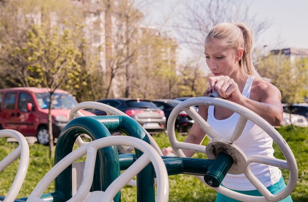 Mujer que ejercita con el equipo del ejercicio en el parque público. Deporte y estilo de vida concepto - aptitud mujer trabajando