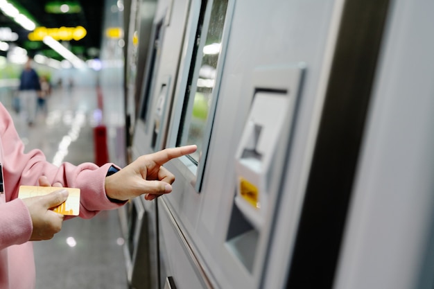 Foto mujer que elige el destino en la máquina del boleto del metro. concepto de transporte