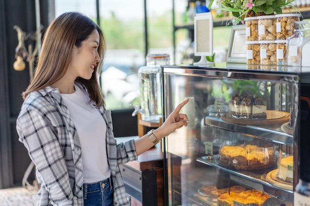 Mujer que elige la torta en un café