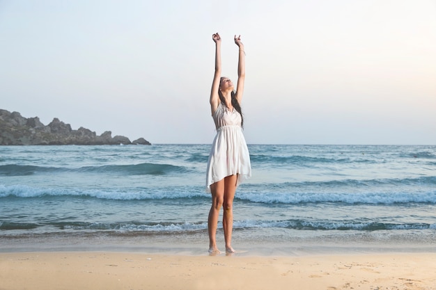 Mujer que estira y que se relaja en la playa