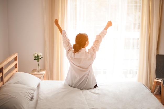 Mujer que se extiende en la cama después de despertarse