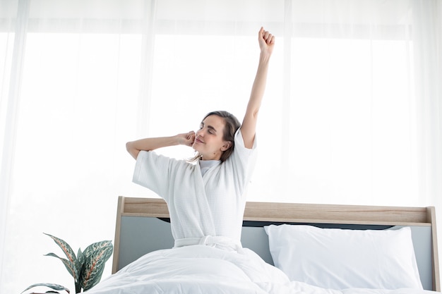 Mujer que se extiende después de despertarse por la mañana.