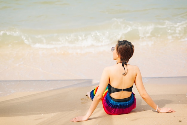 Mujer que goza de la playa que relaja alegre en verano por el agua azul tropical.