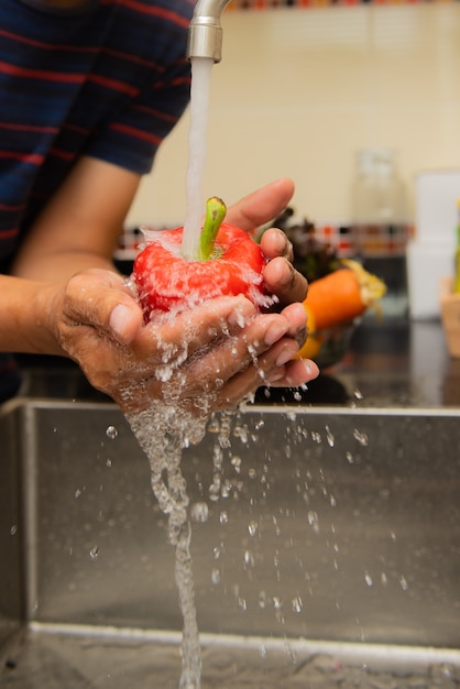 Mujer que lava verduras en la encimera cerca del fregadero en el interior de una cocina moderna