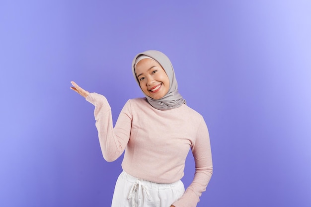 Una mujer que lleva hiyab sonríe y lleva un hiyab rosa.
