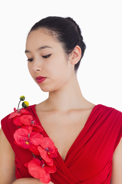 Mujer que llevaba un vestido rojo con una orquídea roja