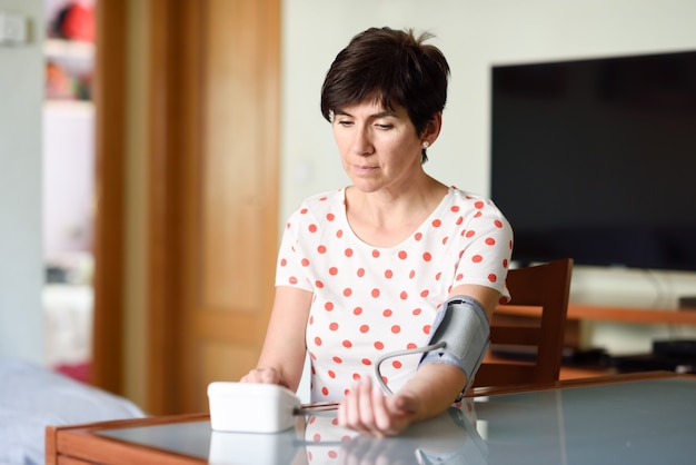 Mujer que mide su propia presión arterial en casa.