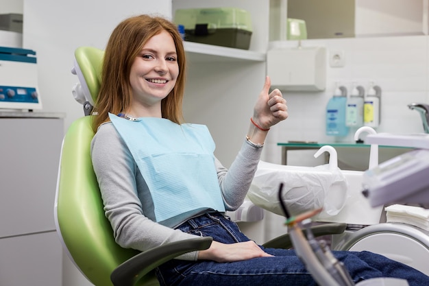 Mujer que muestra el pulgar hacia arriba en la clínica del consultorio del dentista