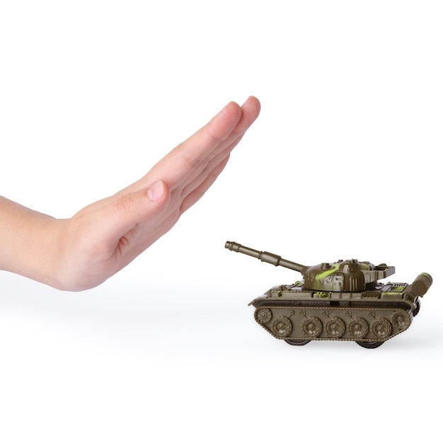 Mujer que muestra la señal de parada frente al tanque de juguete sobre fondo blanco No hay concepto de guerra