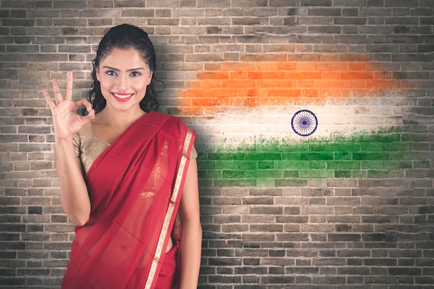 Mujer que muestra el signo OK cerca del fondo de la bandera de la India