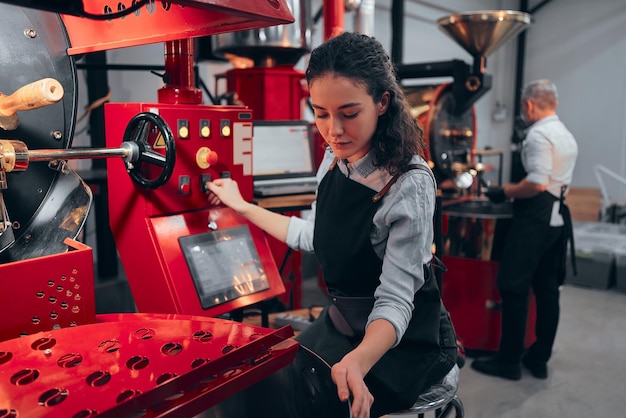 Mujer que opera una tostadora de café en su fábrica.