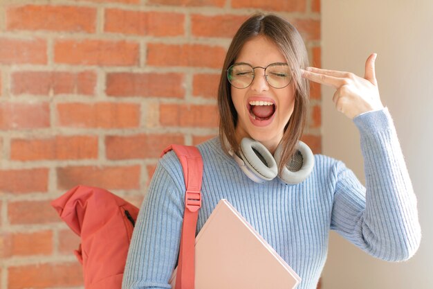 Mujer que parece infeliz y estresada, gesto de suicidio haciendo un signo de pistola con la mano, apuntando a la cabeza