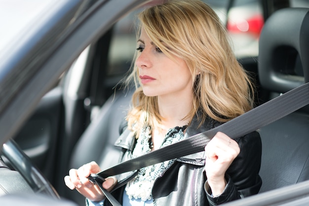 Mujer que se pone el cinturón de seguridad antes de conducir