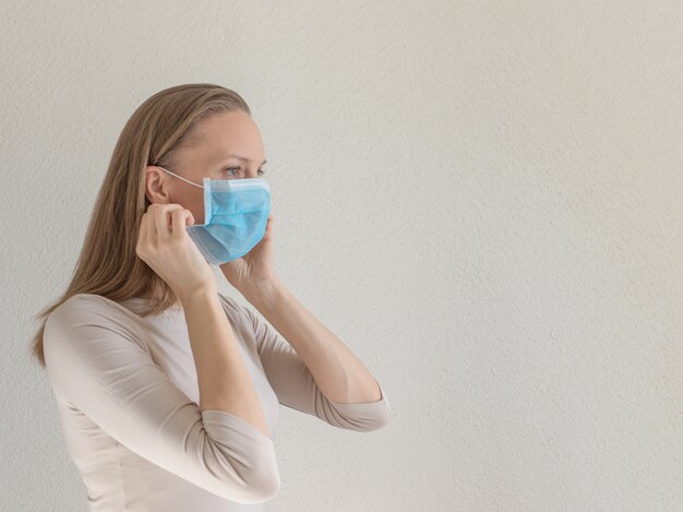 Una mujer que se pone una máscara médica desechable para evitar virus contagiosos