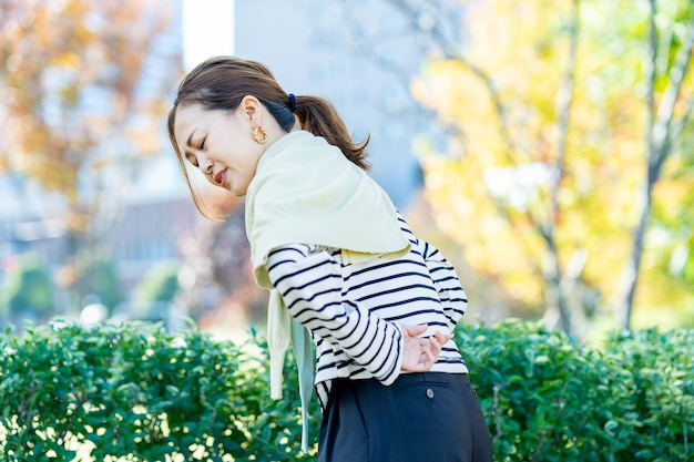 Una mujer que se preocupa por el dolor lumbar al aire libre