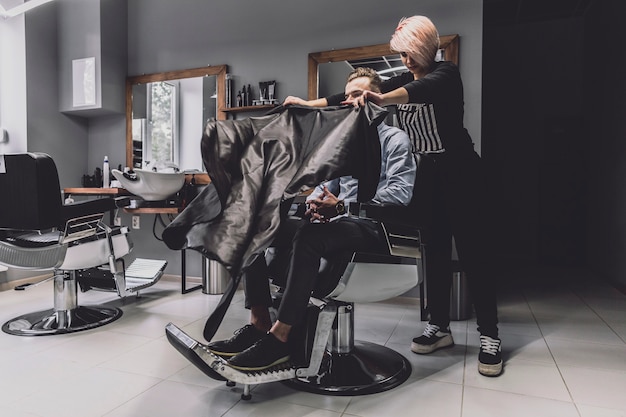 Mujer que prepara al cliente al corte de pelo