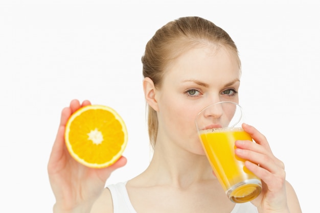 Mujer que presenta una naranja mientras bebe