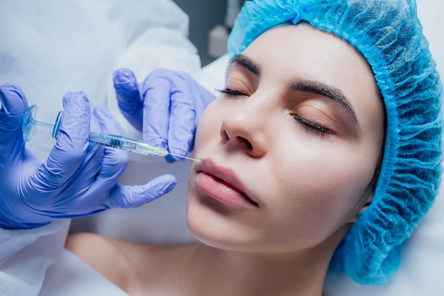 Mujer que recibe la inyección de botox en el spa, inyección de botox en el labio.