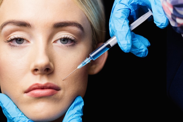 Mujer que recibe la inyección de botox en sus labios