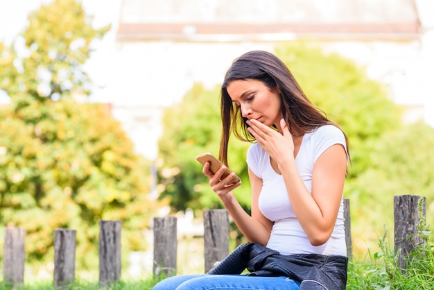 Una mujer que recibe malas noticias en su teléfono inteligente