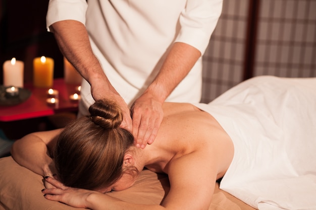 Mujer que recibe el masaje relajante del cuello en el centro de spa. Masajista profesional masculino masajeando el cuello de la clienta. Mujer disfrutando de tratamiento de spa en el lujoso hotel. Recreación, relajación.